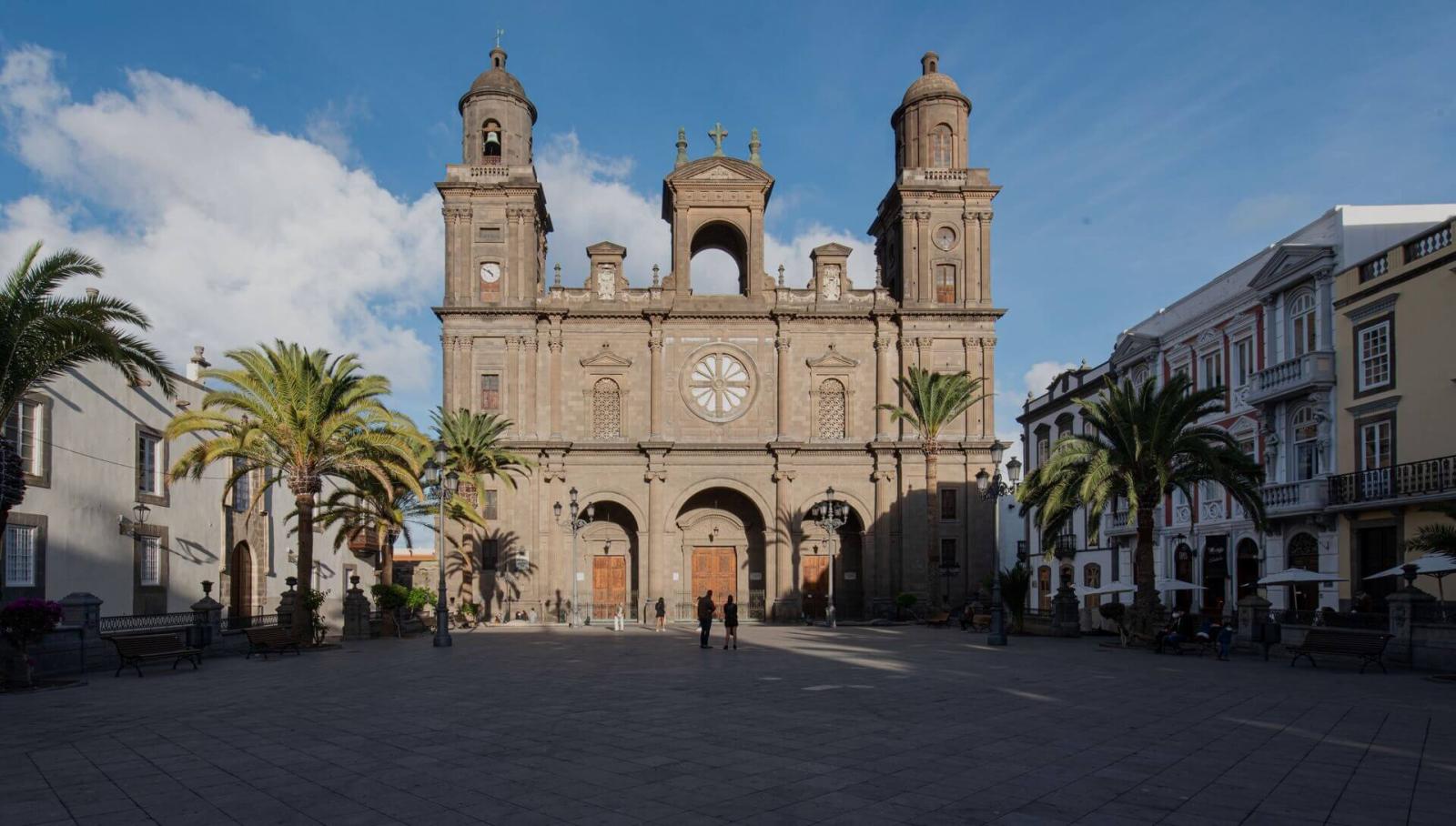 Catedral de Santa Ana en Gran Canaria con palmeras y plaza histórica en primer plano.